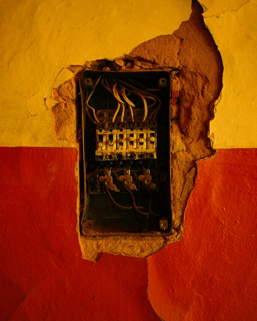 A dangerously outdated electrical panel in a cracked wall